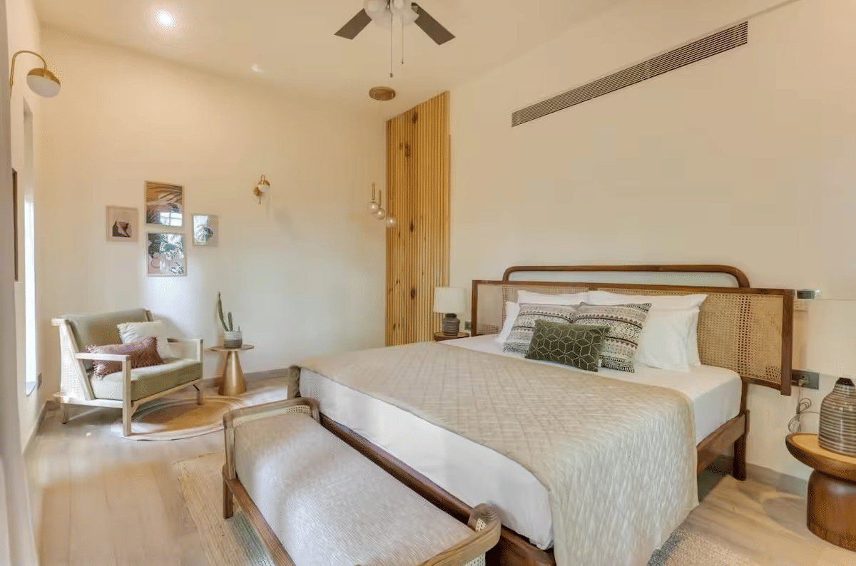 Spacious room with a neatly made bed, bedside table, seating at the foot of the bed, and a cushioned sofa at Lime Tree Villa with Private Pool | Luxury Stay in Goa.